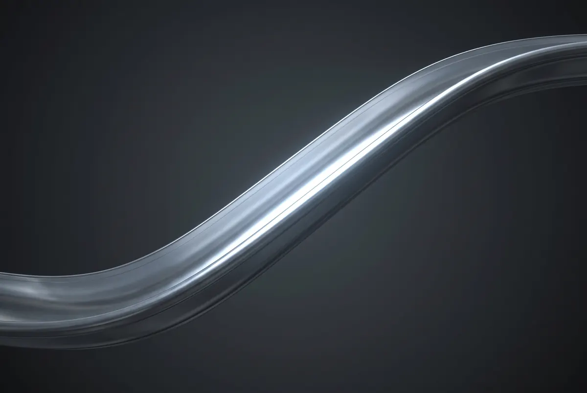 A single unbroken ribbon of formed aluminum gutter curving through darkness, its highlight running the full length with no seam.